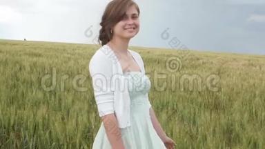 美丽的少女，在田野里高高的绿色小麦穗中。 年轻快乐的女人享受夏天，人与人的和谐